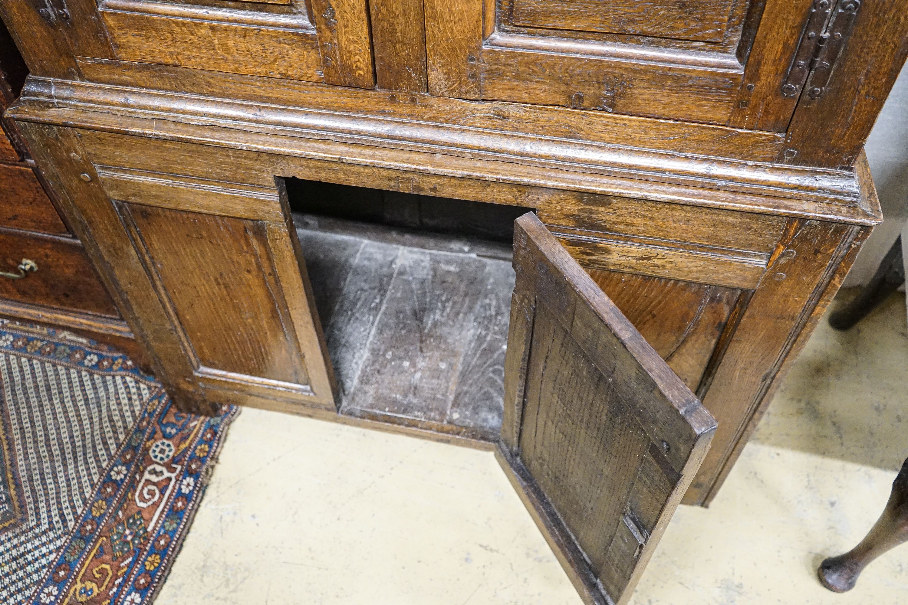 A 17th century style oak press cupboard, with three panelled doors, width 108cm, depth 50cm, height 172cm